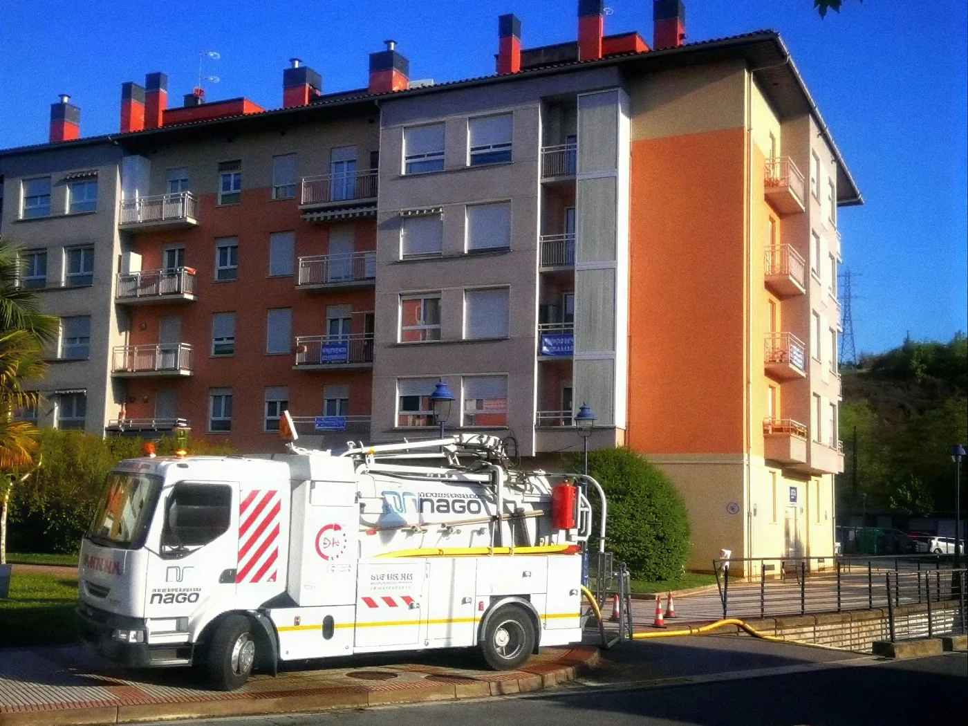 Camión de Desatascos Nago con equipo de agua a presión trabajando junto a un edificio