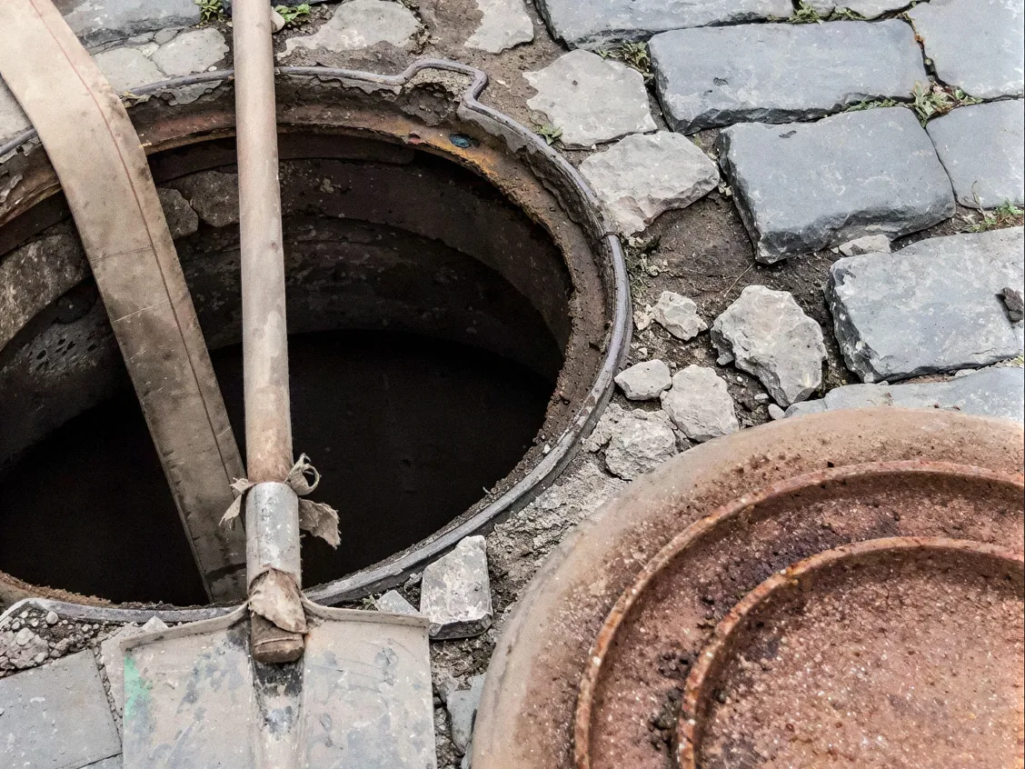Limpieza manual de un pozo de registro en una calle adoquinada