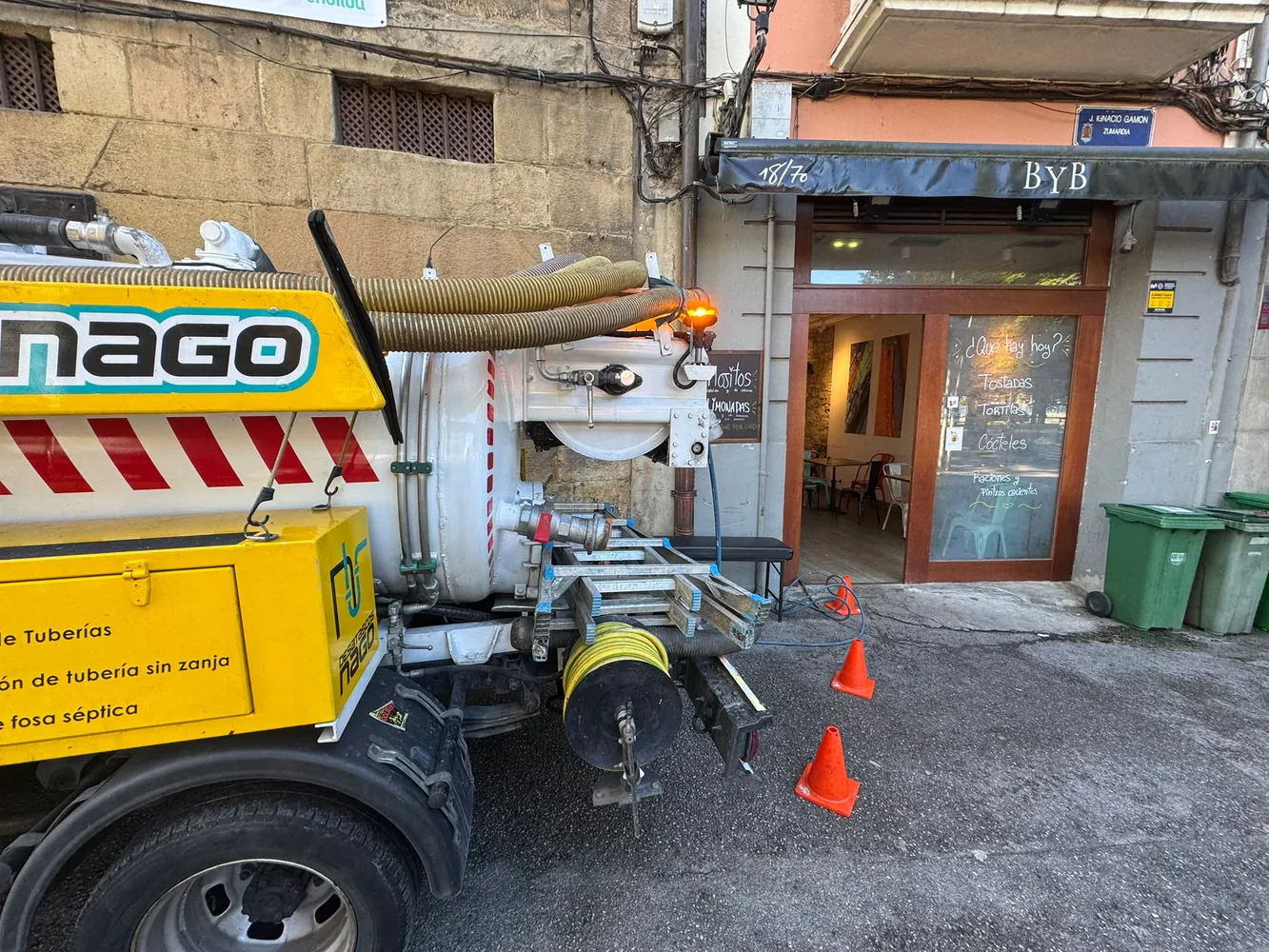 Camión de Desatascos Nago señalizado con conos trabajando en un local de hostelería